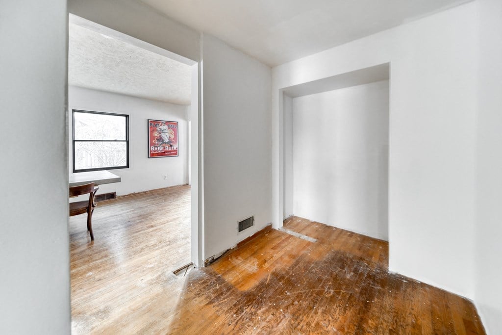 an empty living room with white walls and wood floors
