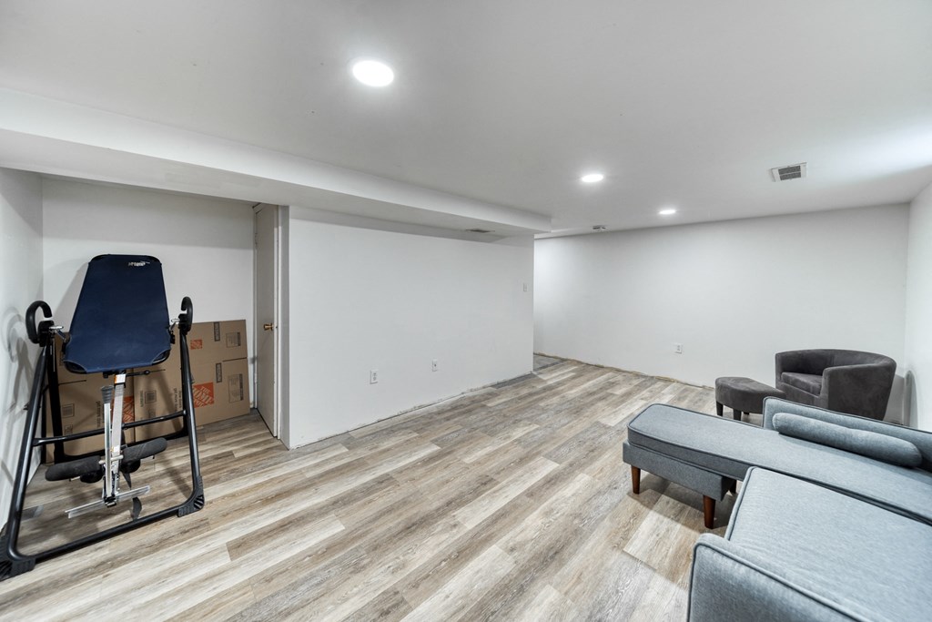 a living room with white walls and wood floors and a wheelchair