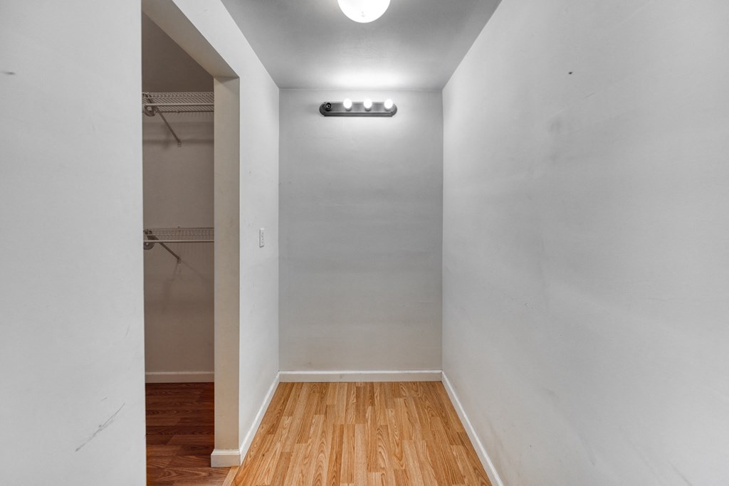 a room with white walls and wood floors and a closet