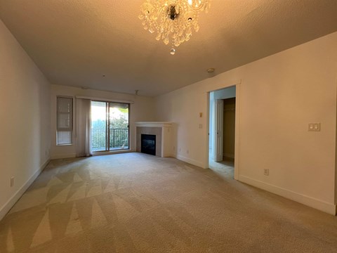 A large, empty room with a chandelier and carpeted floor.