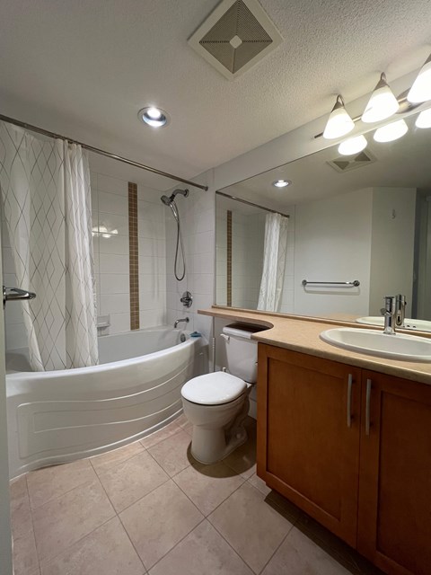 A white toilet sits in a bathroom next to a bathtub.
