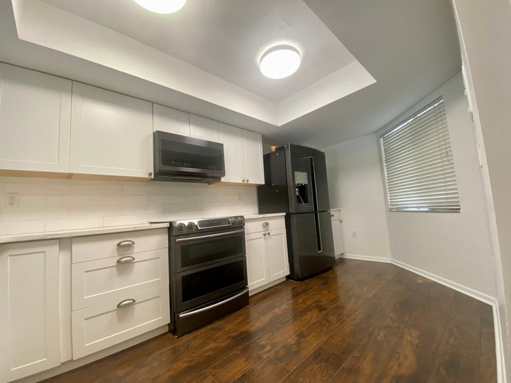 an empty kitchen with white cabinets and a black refrigerator