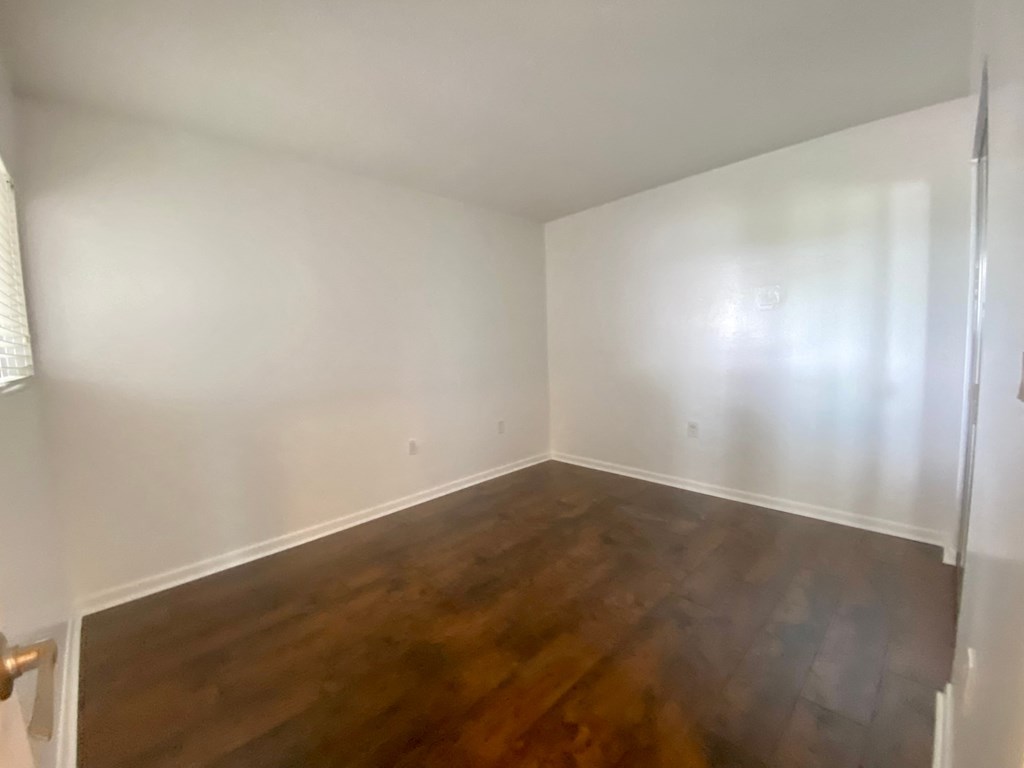an empty room with white walls and wooden floors