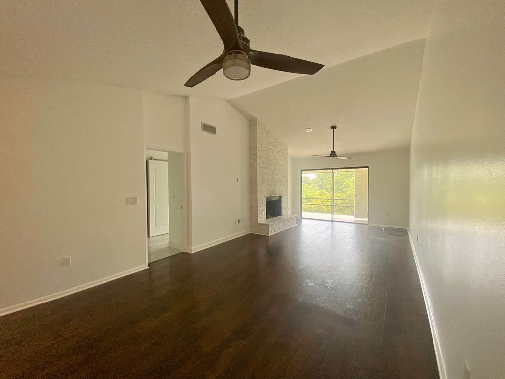 an empty living room with white walls and a ceiling fan