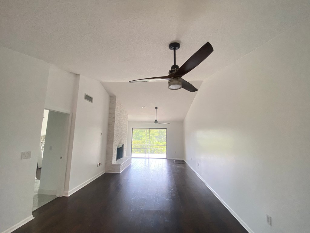 a living room with white walls and a ceiling fan