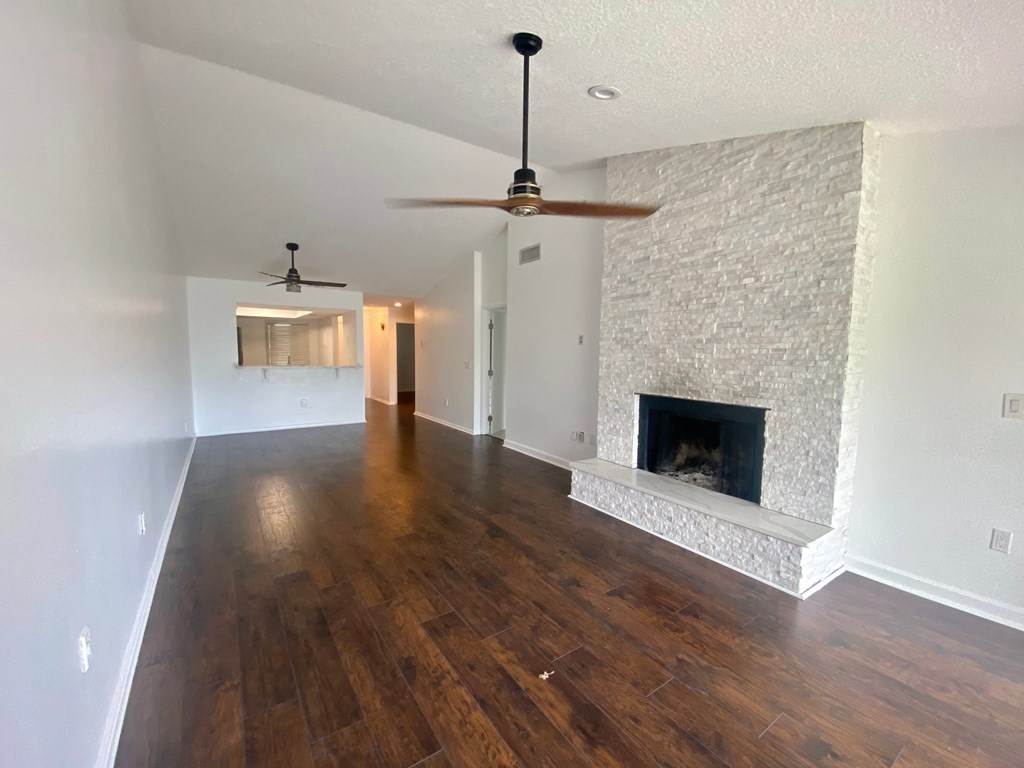 an empty living room with a fireplace and wooden floors