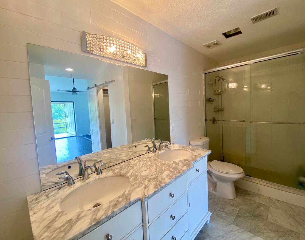 a bathroom with two sinks and a shower and a toilet