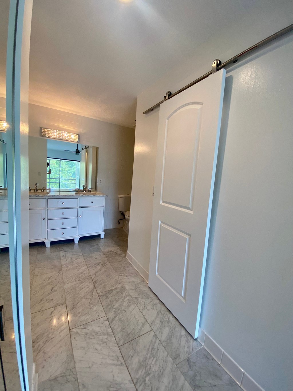 a bathroom with a white door and a sink and a mirror
