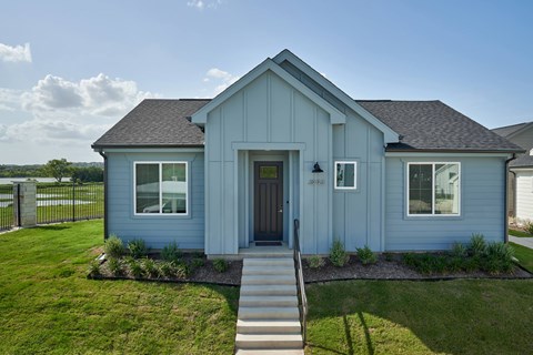 A blue house with a brown door and a small front yard.
