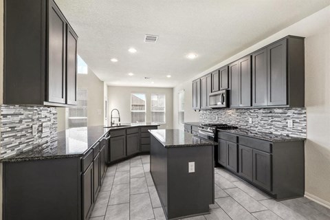 a large kitchen with black cabinets and granite counter tops