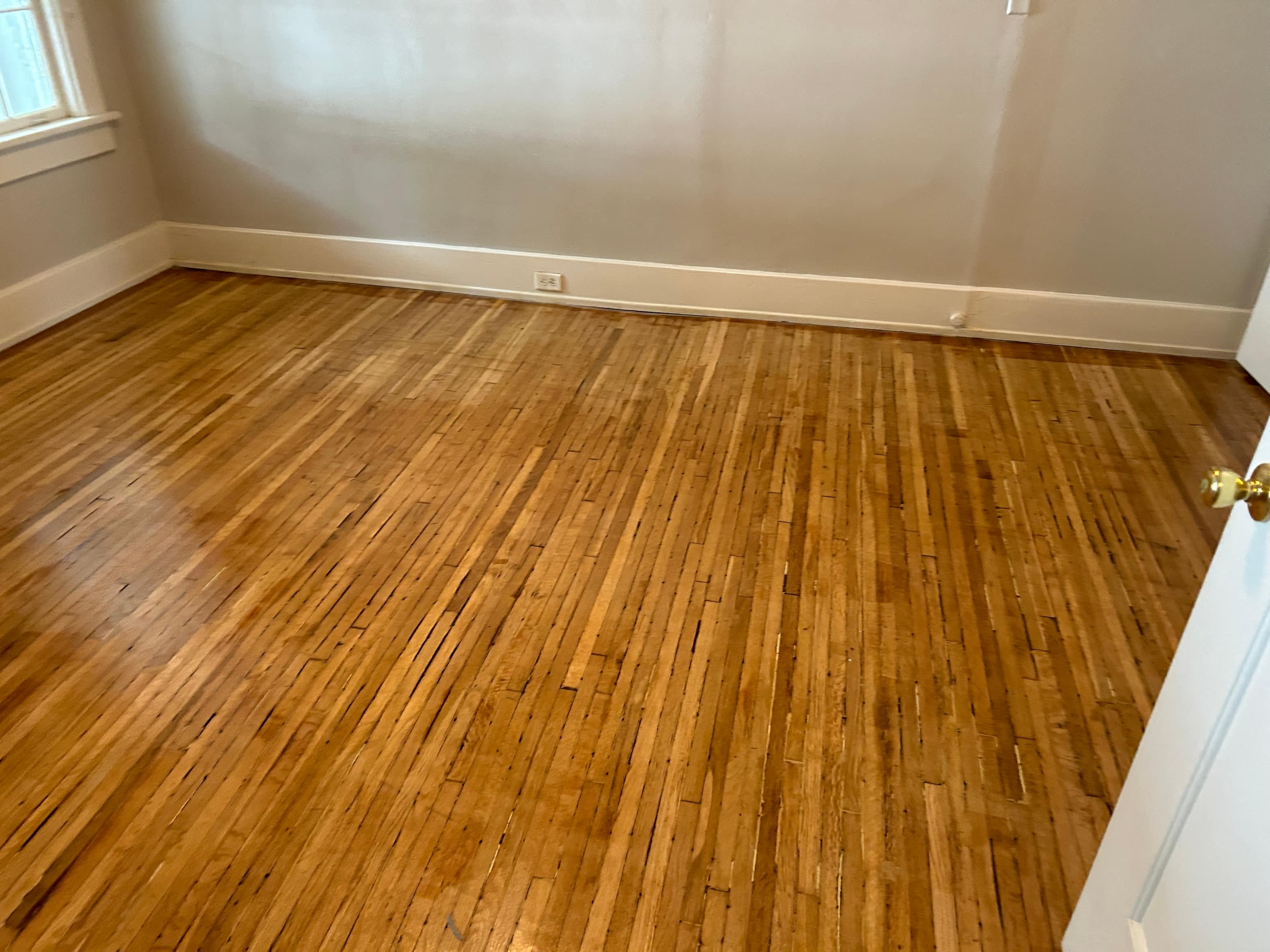 an empty room with wooden floors and a white wall