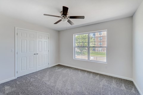an empty living room with a ceiling fan and a window