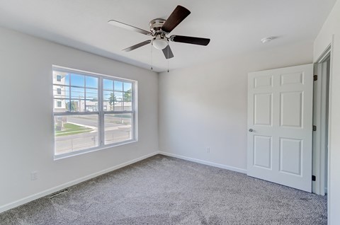 an empty bedroom with a ceiling fan and a window