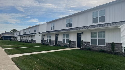 a row of white houses with grass and a sidewalk