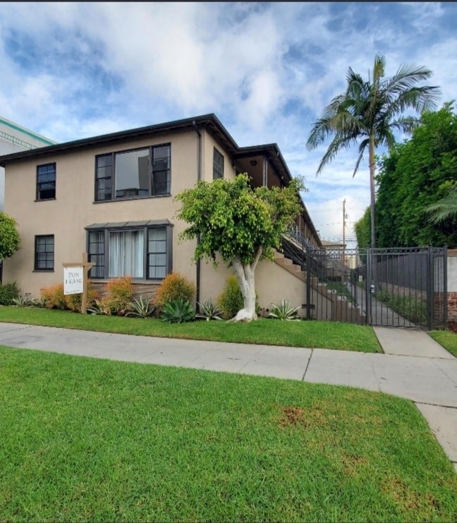 a house with a sidewalk and a palm tree in front of it