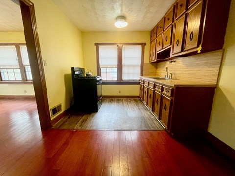 A kitchen with wooden floors and a black piano.