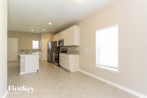 a kitchen with white cabinets and appliances and a large window