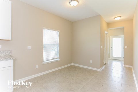 an empty dining room with a door to a hallway and a window