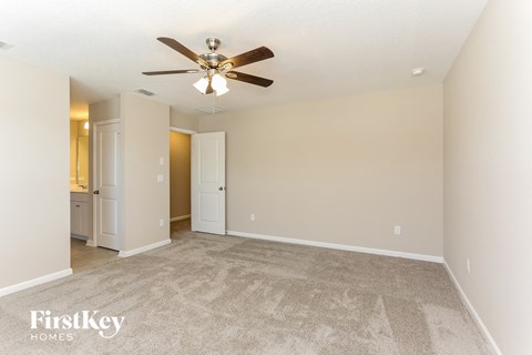 a spacious living room with carpet and a ceiling fan