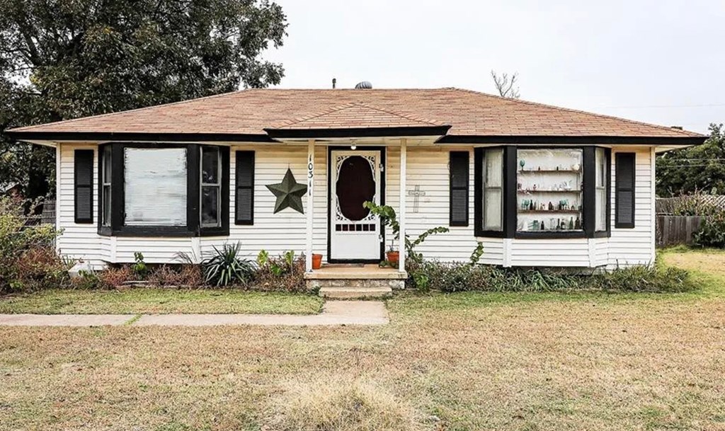 A white house with a brown roof and a star on the front door.