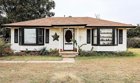 A white house with a brown roof and a star on the front door.