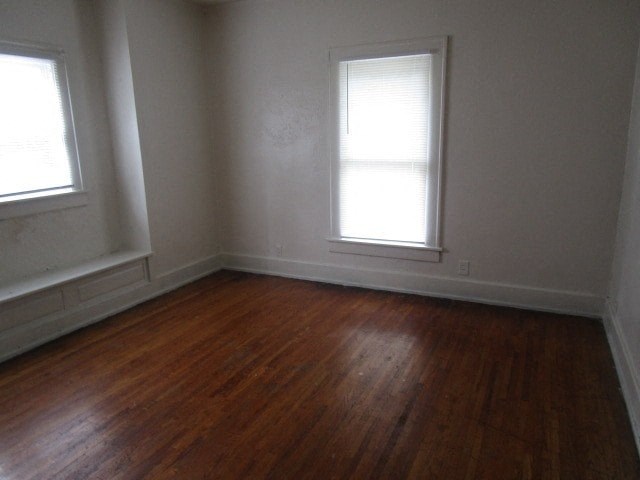 an empty room with a wooden floor and two windows