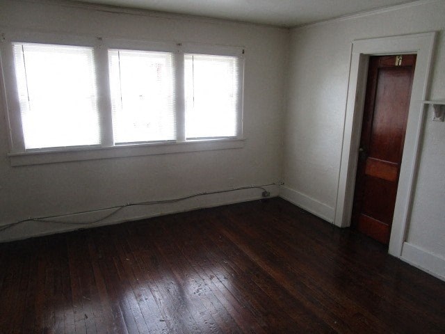 an empty room with wooden floors and three windows