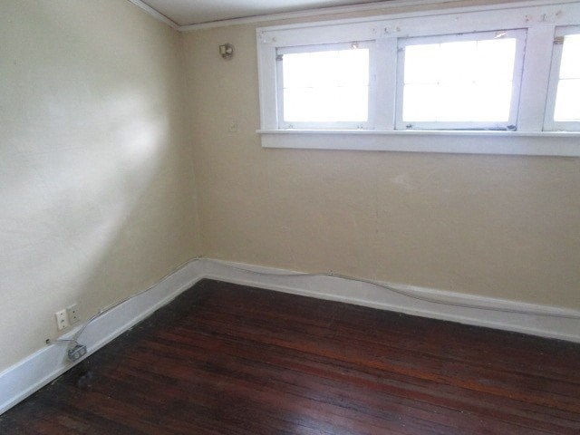 a small room with a wooden floor and two windows