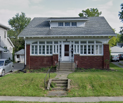 a small brick house with a front porch and stairs