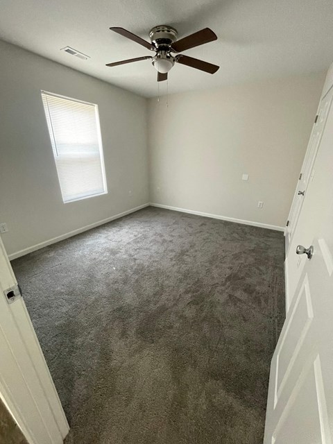 a bedroom with a carpeted floor and a ceiling fan