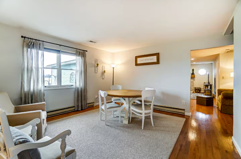 A living room with a grey carpet and white chairs.