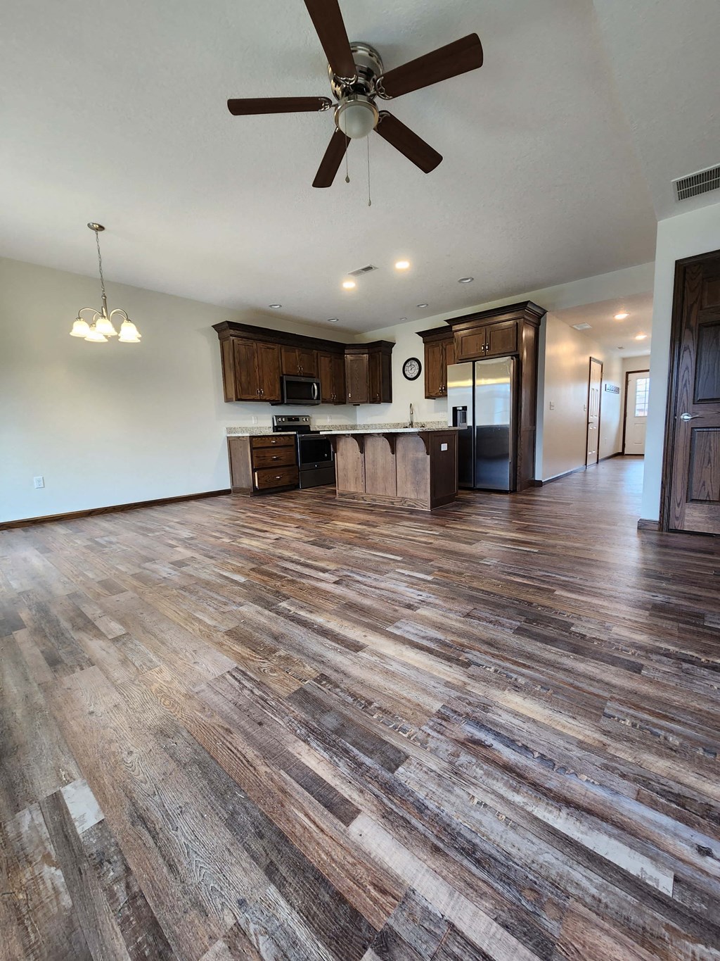 a kitchen and living room with wood flooring and a ceiling fan