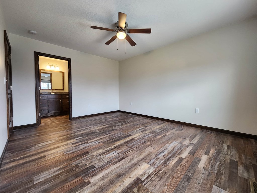 an empty living room with wood floors and a ceiling fan