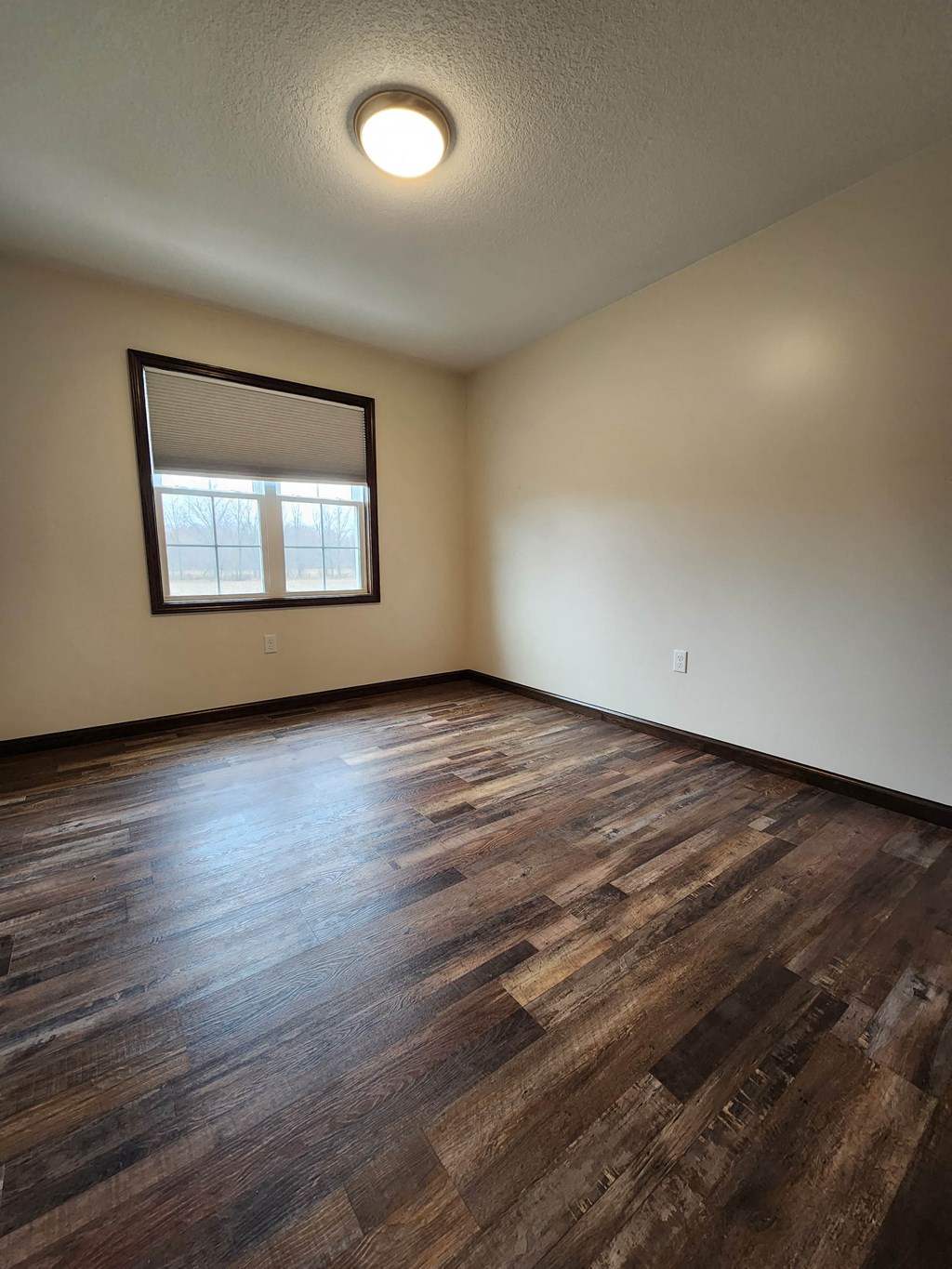 an empty living room with wood floors and a window