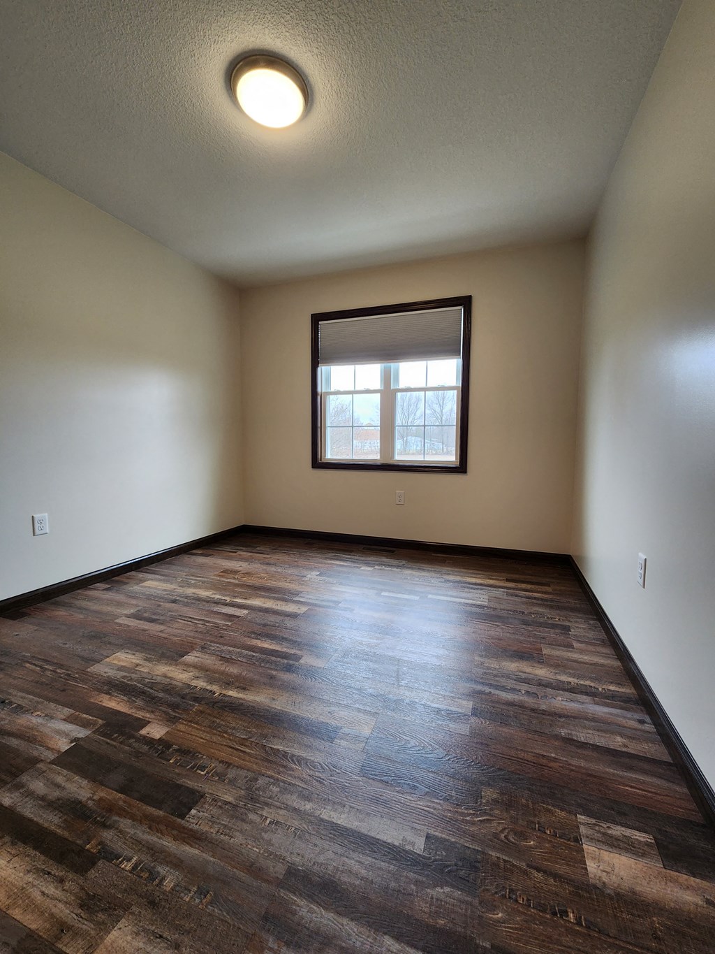 an empty living room with wood floors and a window