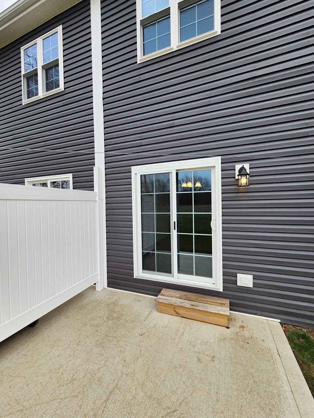 the side of a house with a patio and a white fence