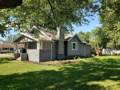 a white and gray house with a yard and trees