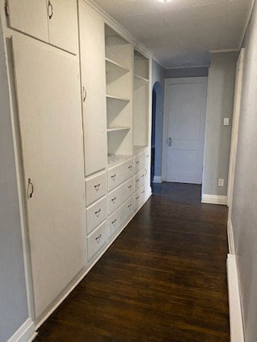 a hallway with white cabinets and drawers and a wooden floor
