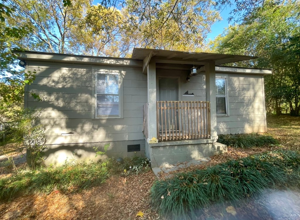 a small gray house with a porch and a fence