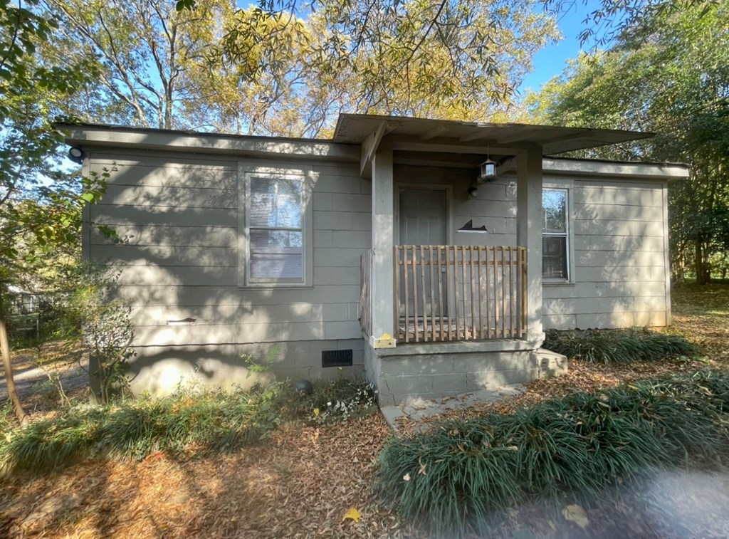 a small gray house with a porch and a tree