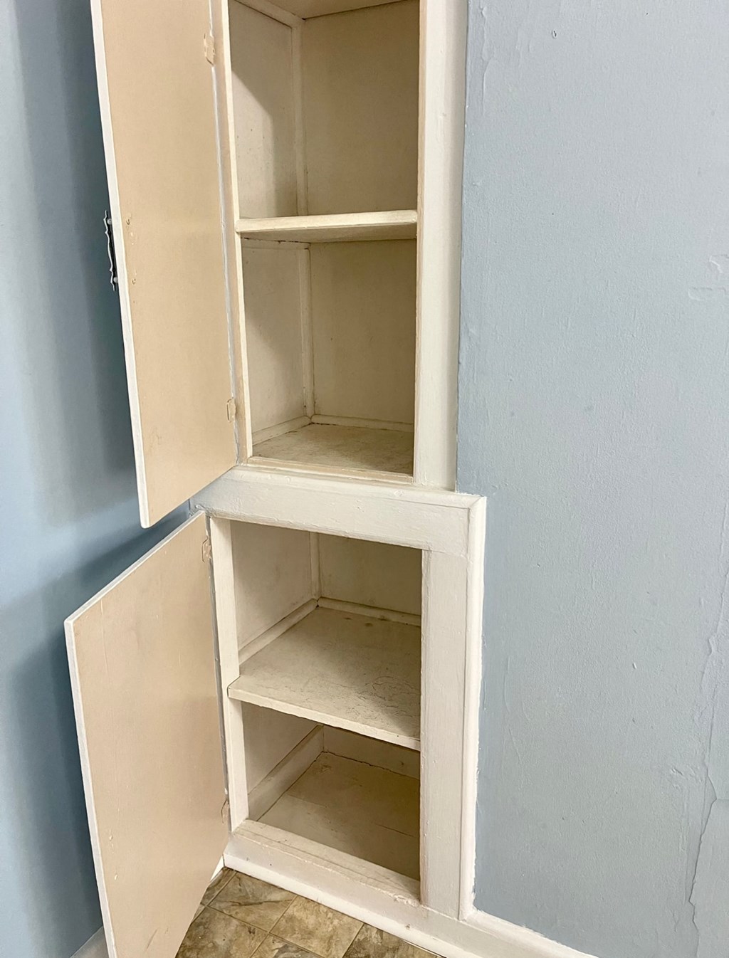 a white cabinet with three shelves on a blue wall
