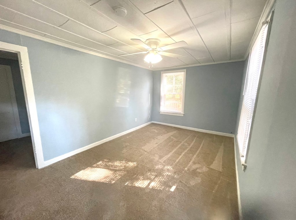 an empty room with blue walls and a ceiling fan