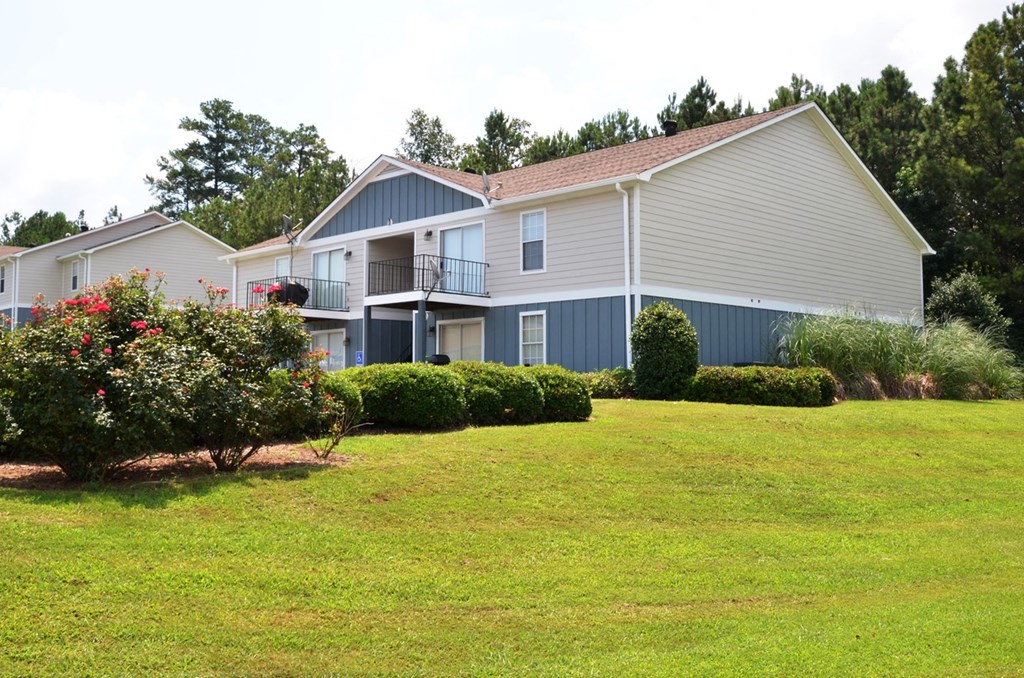 a house with a green lawn and bushes in front of it