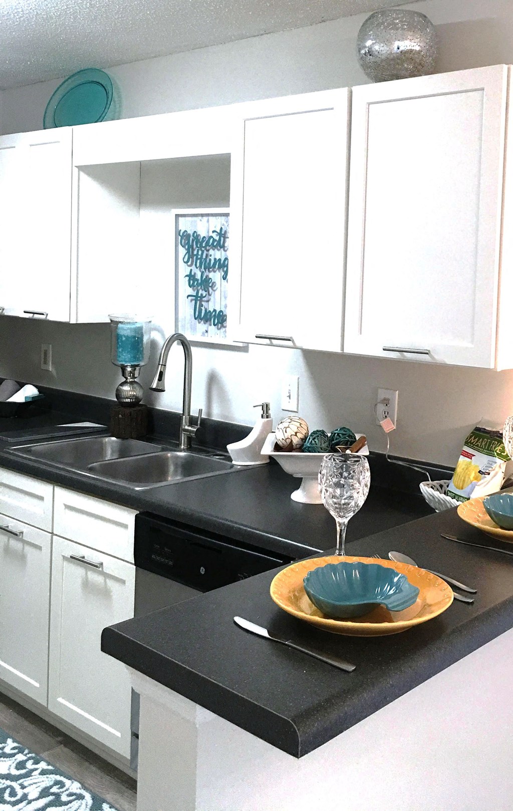 a white kitchen with a black counter top and a sink