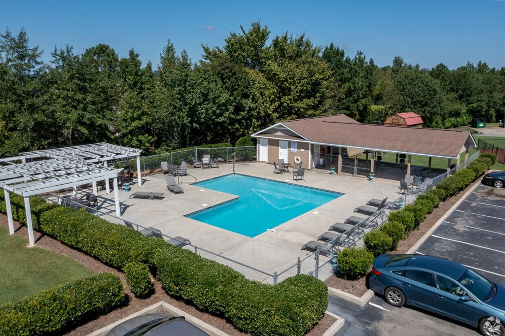 a resort style pool with lounge chairs around it and a house with a swimming pool