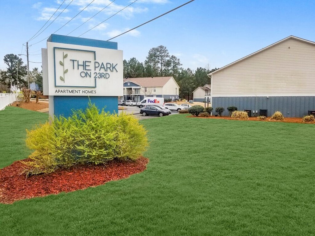 a sign for the park on 520 in front of a lawn and a house