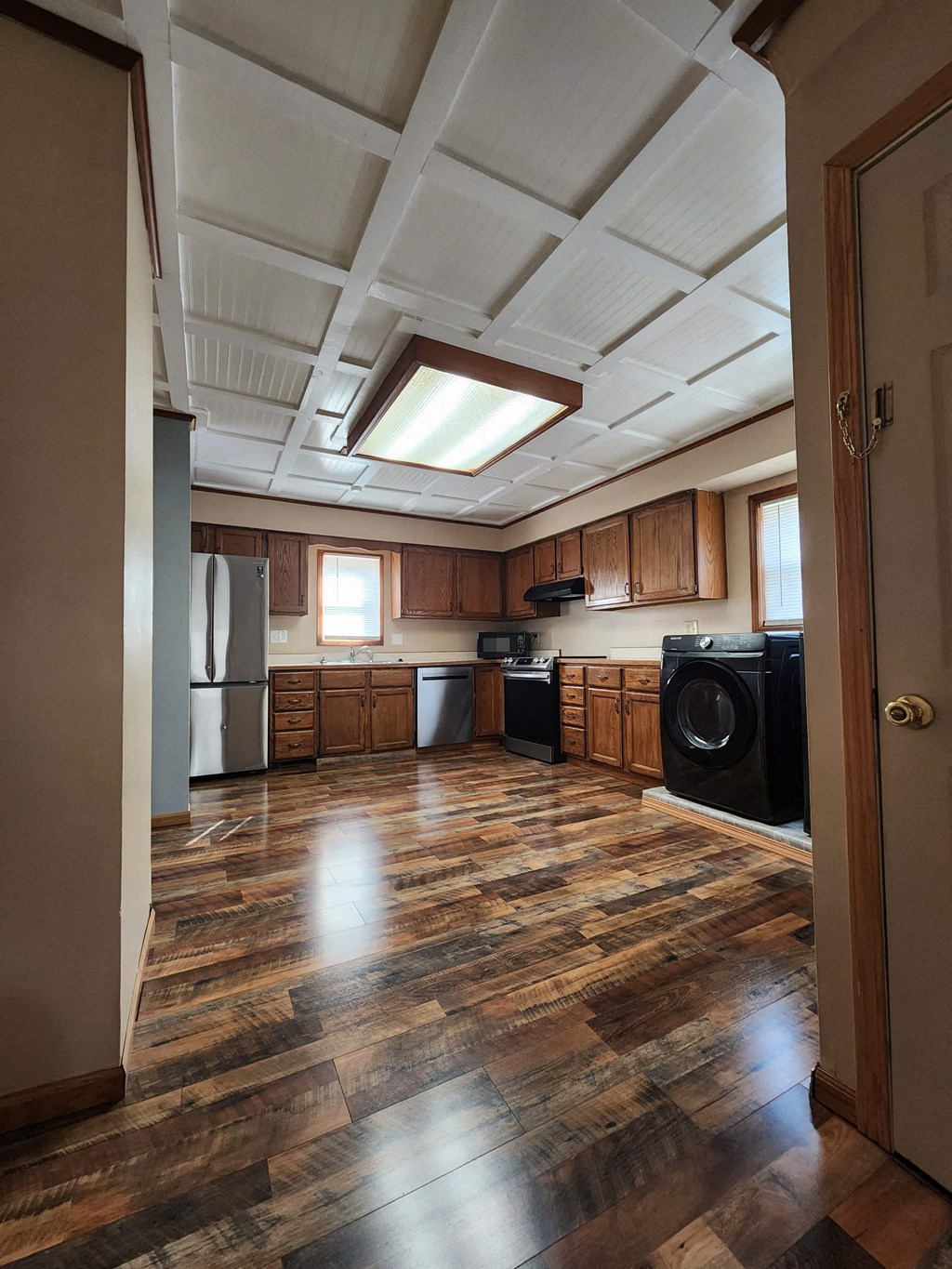 an empty kitchen with wooden floors and cabinets and a window