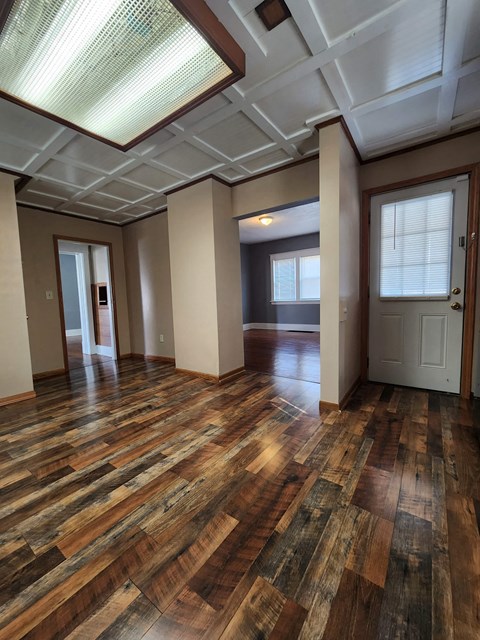 an empty living room with wood floors and a door