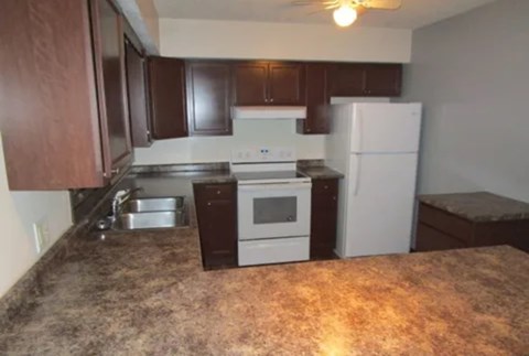 A kitchen with brown cabinets and a granite countertop.