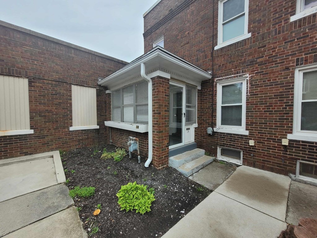 the front of a brick building with a porch and steps